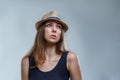 Beautiful young woman in hat and black shirt is looking up isolated on gray background in a studio close up Royalty Free Stock Photo