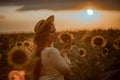 Beautiful young woman in a hat enjoying nature on a field of sunflowers at sunset. Summer. Attractive brunette with long Royalty Free Stock Photo