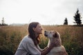 Beautiful young woman having fun summer sunset with her lovely dog on the straw field background Royalty Free Stock Photo