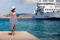 Beautiful young woman in hat relax on wooden pier on Sardinia beach