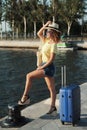 Beautiful young woman in hat with suitcase and wine glass waiting a ship for summer trip. Royalty Free Stock Photo