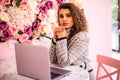 Beautiful young woman hat working on laptop and smiling while sitting outdoors Royalty Free Stock Photo