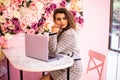 Beautiful young woman hat working on laptop and smiling while sitting outdoors Royalty Free Stock Photo