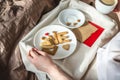 Young woman have a romantic Breakfast in morning bed. Coffee and word love from cookies. Surprise on Valentine`s day Royalty Free Stock Photo