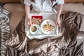 Young woman have a romantic Breakfast in morning bed. Coffee and word love from cookies. Surprise on Valentine`s day Royalty Free Stock Photo