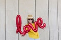 Beautiful young woman having fun outdoors with a red balloon with a love word shape. Casual clothing. wearing hat and modern Royalty Free Stock Photo