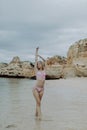 Beautiful young woman having fun on the sea with raised arms and enjoying the beauty views of rocky beach Royalty Free Stock Photo