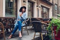 Beautiful young woman having orange juice in outdoor cafe and showing tongue to passer-by Royalty Free Stock Photo