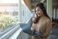 A beautiful young woman with headphone using and working on laptop computer Royalty Free Stock Photo