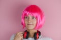 Young woman with headphones around her neck on a pink background