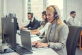 Beautiful young woman with headset using laptop while talking with a client. Online customer care support service. Royalty Free Stock Photo