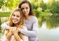 A beautiful young woman with her adult mother hugging on the background of the lake, on a summer day in the park. Royalty Free Stock Photo