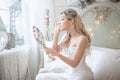Beautiful young woman in her bedroom with a mirror. Bride`s morning or vintage boudoir
