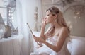 Beautiful young woman in her bedroom with a mirror. Bride`s morning or vintage boudoir