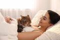 Beautiful young woman with her cute cat on bed Royalty Free Stock Photo