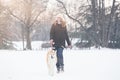 Beautiful young woman and her dog akita walking in park on snow Royalty Free Stock Photo