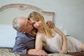 Beautiful Young Woman with Her Senior Lover Lying on the Bed. Man Kissing His Girlfriend. Portrait of Happy Lovely Couple Royalty Free Stock Photo