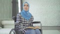 A beautiful young woman in a hijab is blind or weakly imposing, a wheelchair reading a braille font.