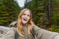 Beautiful young woman hiker taking selfie in the mountain forest. Looking at camera and smile. Travel and active life Royalty Free Stock Photo