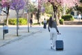 Beautiful young woman, Hispanic, brown hair, wearing striped sweater, linen pants, walking with her suitcase at sunset, in a park Royalty Free Stock Photo