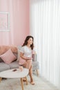 Beautiful young woman hold cup of coffee relaxing on the couch, sofa in a living room, happy smile day dreaming with tea mug in Royalty Free Stock Photo