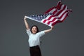 beautiful young woman holding american flag in raised hands and smiling at camera
