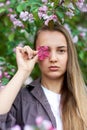 Beautiful young woman holding an apple tree flower in the park