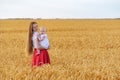 Beautiful young woman holding baby in wheat field. Weekend outsides