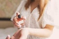 Beautiful young woman holding a bottle of perfume and applying it on her wrist Royalty Free Stock Photo