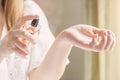 Beautiful young woman holding a bottle of perfume and applying it on her wrist Royalty Free Stock Photo