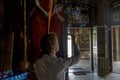 Beautiful young woman holding buddhist incense sticks in the temple