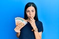 Beautiful young woman holding bunch of 50 euro banknotes mouth and lips shut as zip with fingers