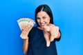Beautiful young woman holding bunch of 50 euro banknotes pointing to you and the camera with fingers, smiling positive and Royalty Free Stock Photo