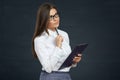 Beautiful young woman holding clipboard with pen thinking. Royalty Free Stock Photo