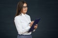 Beautiful young woman holding clipboard with pen thinking. Royalty Free Stock Photo