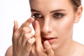 Beautiful young woman holding a contact lens on her finger. Eye care and choice of means to improve vision