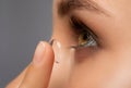 Beautiful young woman holding a contact lens on her finger. Eye care and choice of means to improve vision