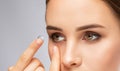 Beautiful young woman holding a contact lens on her finger. Eye care and choice of means to improve vision