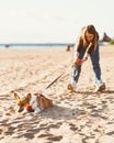 Beautiful young woman holding Corgi puppy dog pulling leash. Female walking with dog Royalty Free Stock Photo