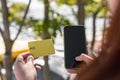 Beautiful young woman holding a credit card using mobile phone on the street. Online shopping concept Royalty Free Stock Photo