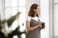 Beautiful young woman holding cup of coffee, looking out window Royalty Free Stock Photo