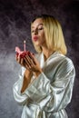 Beautiful young woman holding a cupcake with a colored candle in a silk robe. Royalty Free Stock Photo