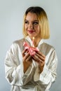 Beautiful young woman holding a cupcake with a colored candle in a silk robe. Royalty Free Stock Photo