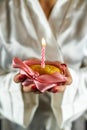 Beautiful young woman holding a cupcake with a colored candle in a silk robe. Royalty Free Stock Photo