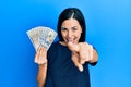 Beautiful young woman holding dollars pointing to you and the camera with fingers, smiling positive and cheerful Royalty Free Stock Photo