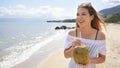 Beautiful young woman holding a fresh coconut enjoying on tropical beach. Girl relax on the beach in her travel holiday holding a Royalty Free Stock Photo