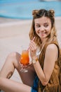 beautiful young woman holding glass of summer cocktail while sitting Royalty Free Stock Photo