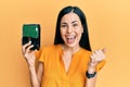 Beautiful young woman holding hard disk screaming proud, celebrating victory and success very excited with raised arms Royalty Free Stock Photo