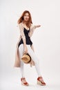 Beautiful young woman holding a hat on white isolated background, photo in full length