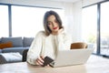 Young woman using cell phone and notebook while sitting at desk at home Royalty Free Stock Photo